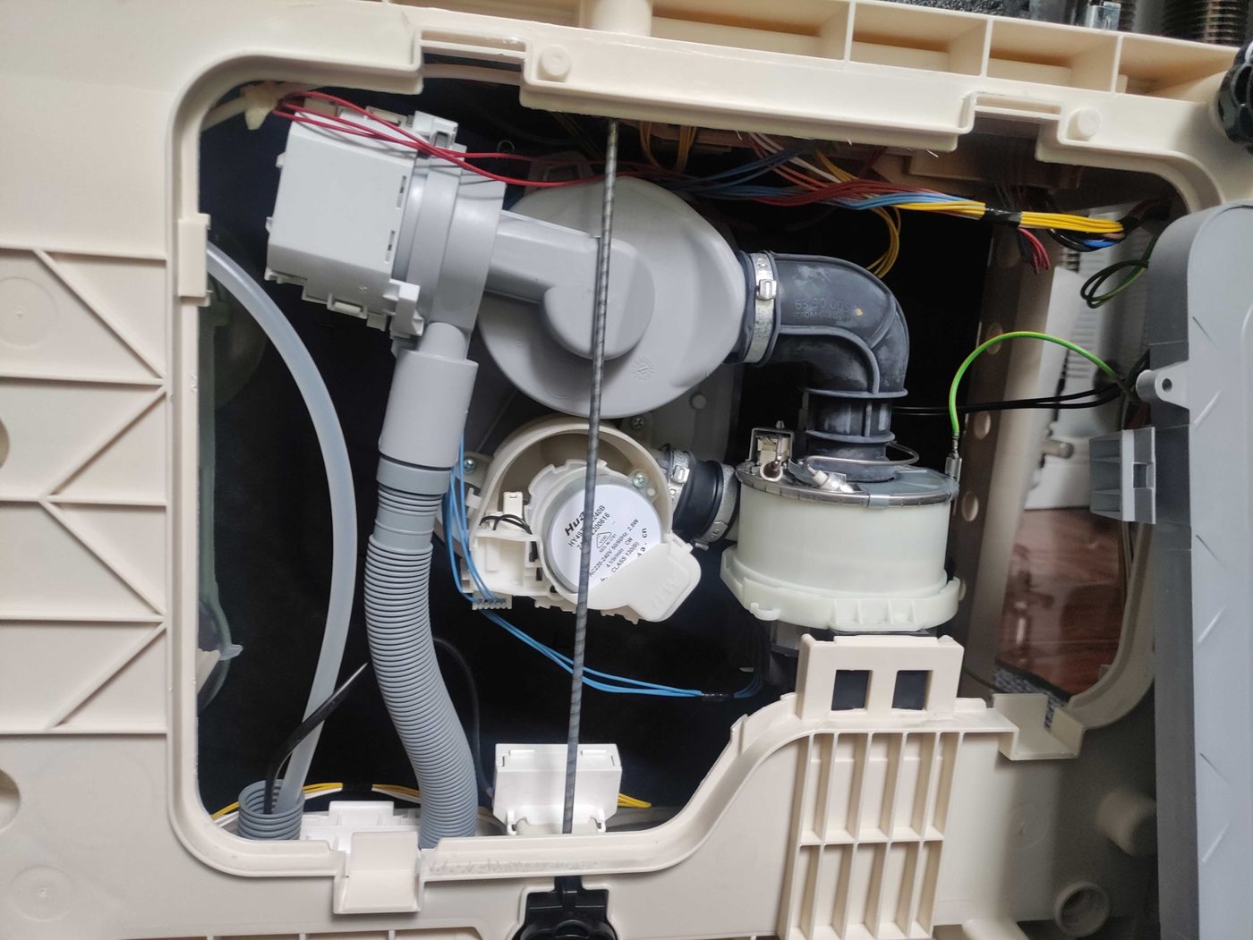 Dishwasher pump and hose components exposed during repair diagnostics